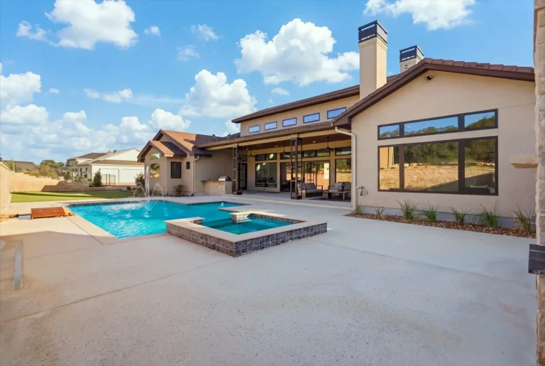 Backyard pool and spa with the home's clerestory windows and chimney beyond in Boerne, TX