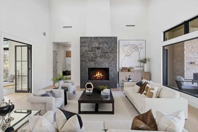 Seating area facing a geometric tile fireplace beneath tall white walls and clerestory windows in a Boerne custom home