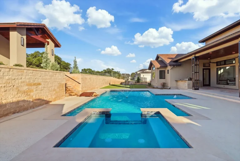 Geometric pool and raised spa with fountain jets behind a Boerne luxury custom home
