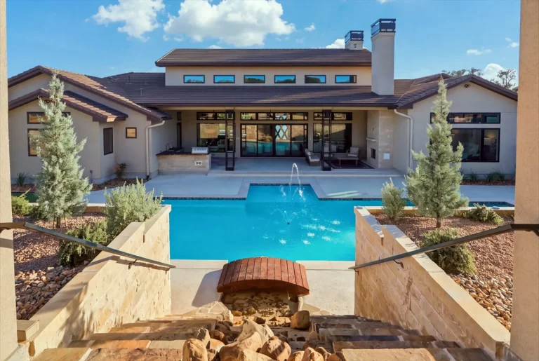 View down limestone garden stairs to the pool and covered patio of a Boerne, TX custom home