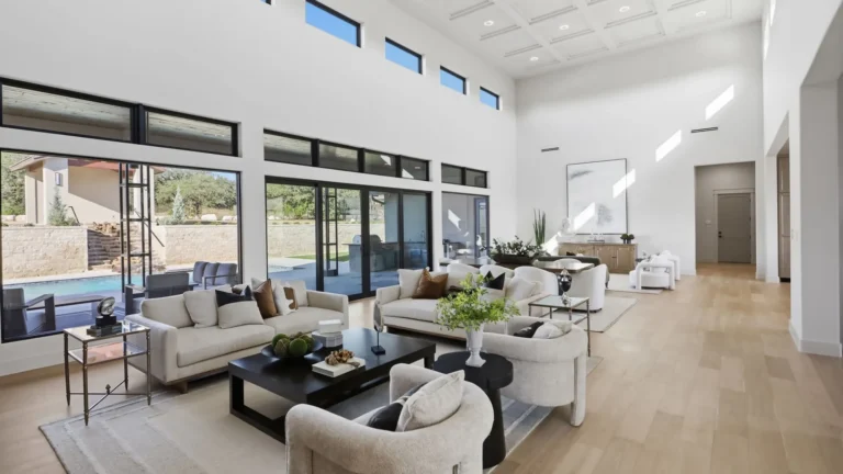 Living area with floor-to-ceiling glass looking out to the pool and limestone retaining walls in Boerne, TX