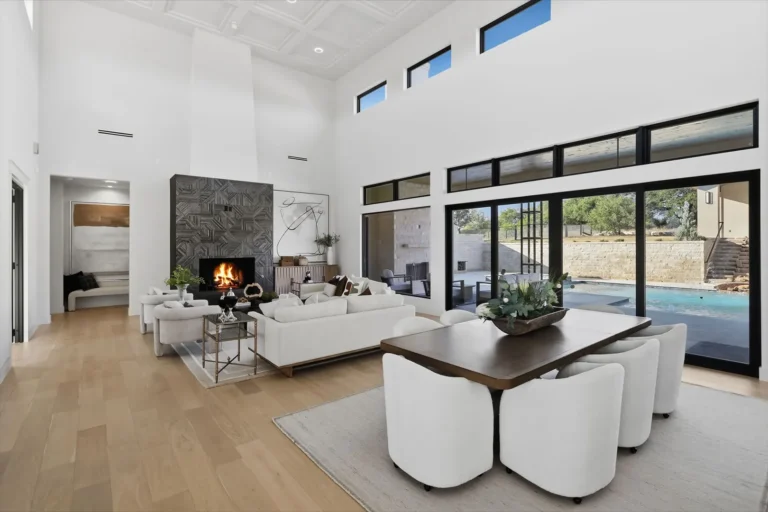 Open dining and living plan with a fireplace and pool views in a Boerne luxury custom home