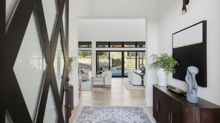 Entry with a black diamond-pattern pivot door opening to the great room of a Boerne, TX luxury custom home