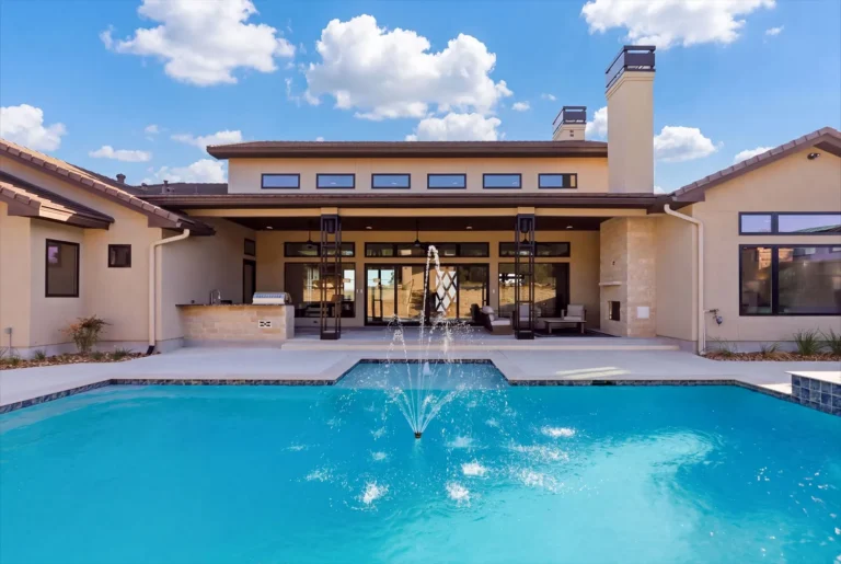 Rear elevation of a Boerne luxury custom home with a long covered patio, clerestory windows and pool