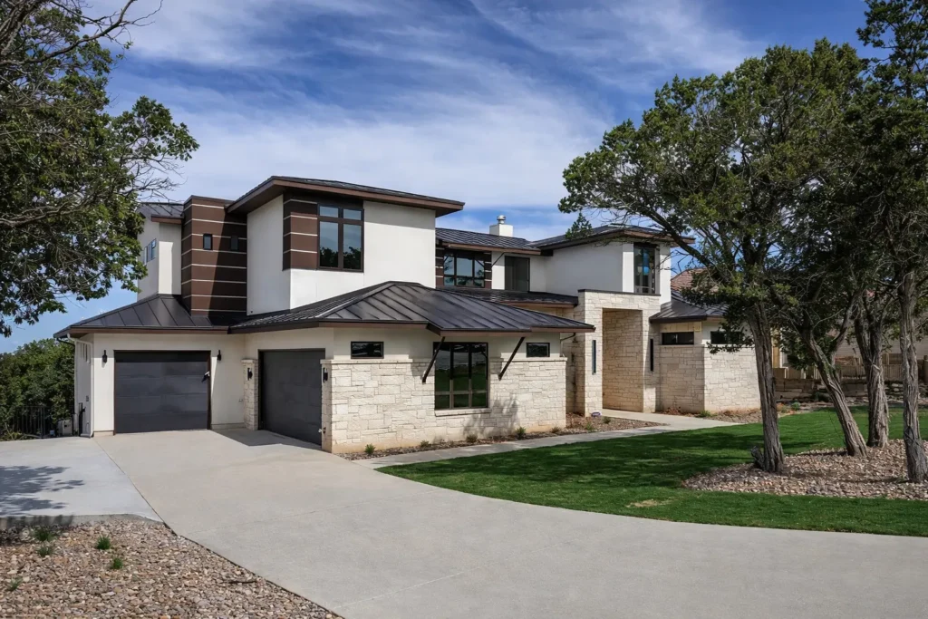 Contemporary custom home with limestone, white stucco, wood-look accent cladding, a metal roof and two-car garage
