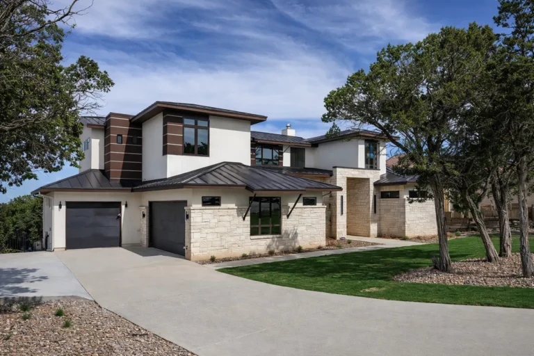 Contemporary custom home with limestone, white stucco, wood-look accent cladding, a metal roof and two-car garage
