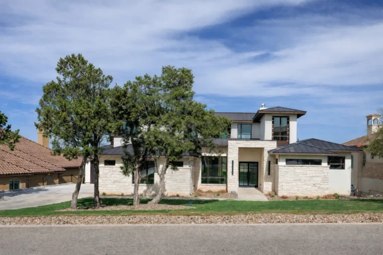 Two-story Hill Country contemporary custom home with white limestone, stucco and a standing-seam metal roof under live oaks