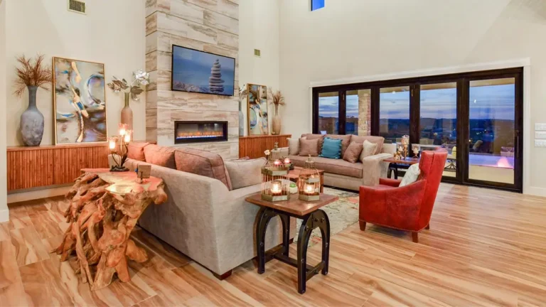 Great room with a floor-to-ceiling limestone fireplace, linear firebox and a wall of glass doors to a deck with Hill Country views