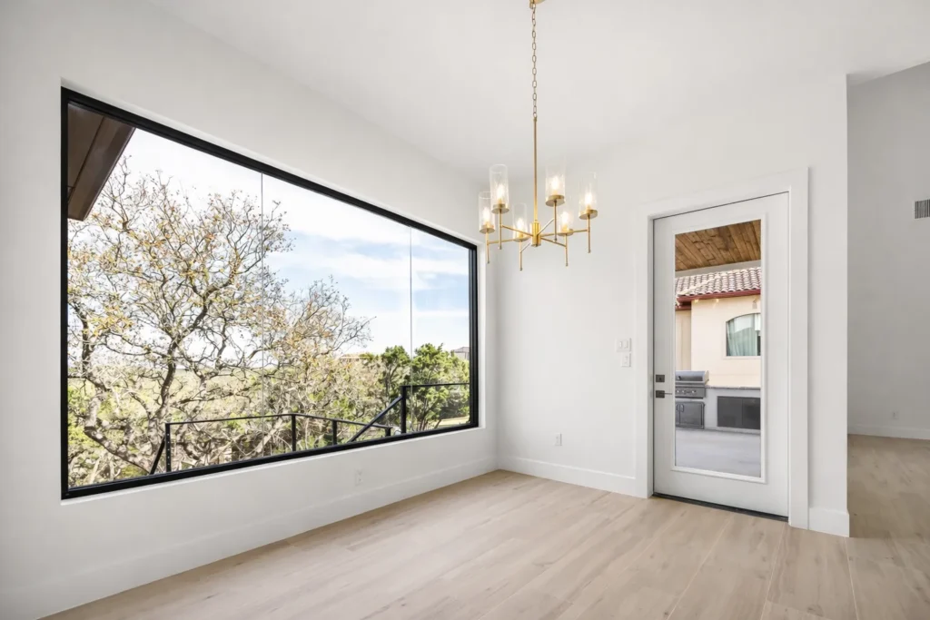 Breakfast nook with a brass chandelier and an oversized picture window looking into the oak canopy