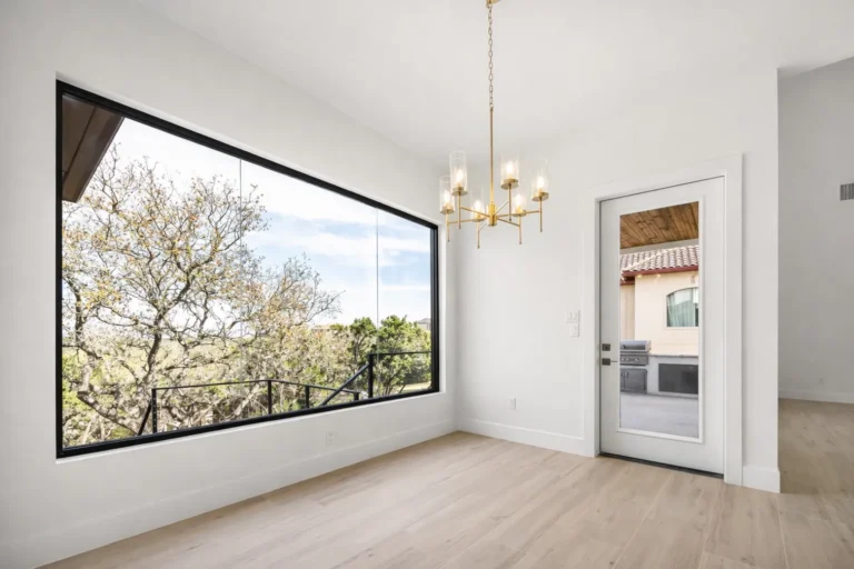Breakfast nook with a brass chandelier and an oversized picture window looking into the oak canopy