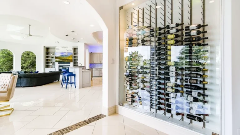 Glass-enclosed wine wall with floating bottle racks beside an arched opening to the family room and kitchen