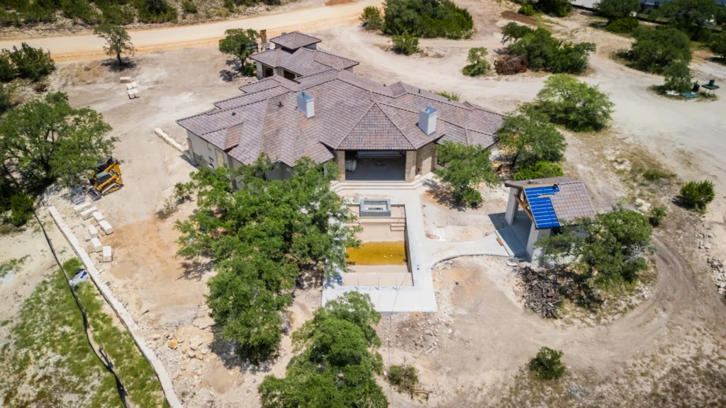 Exterior aerial photo of a custom modern tuscan estate by Genesis Custom Homes in Pecan Springs, Boerne, TX - showing a pool and a cabana on a large view of the lot