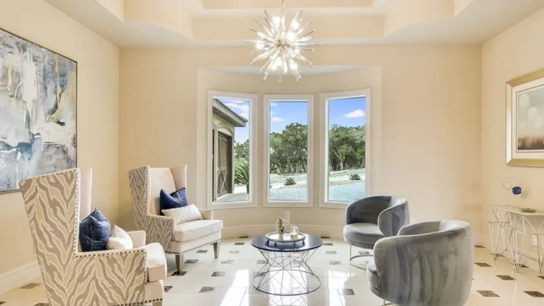 Sitting room with a starburst chandelier, bay window, velvet swivel chairs and marble floors with diamond inserts