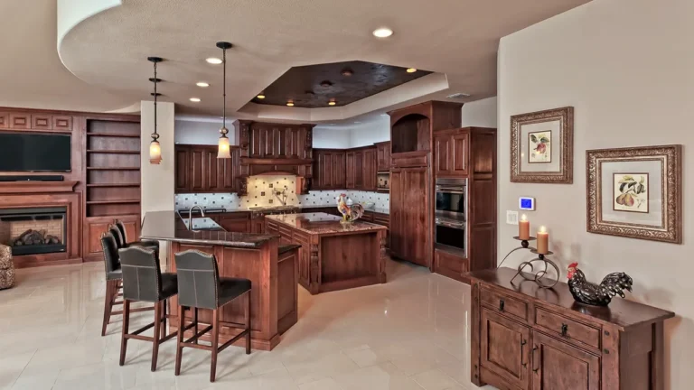 Kitchen with two alder islands, a breakfast bar and built-in shelving beside a fireplace under a dark tray ceiling