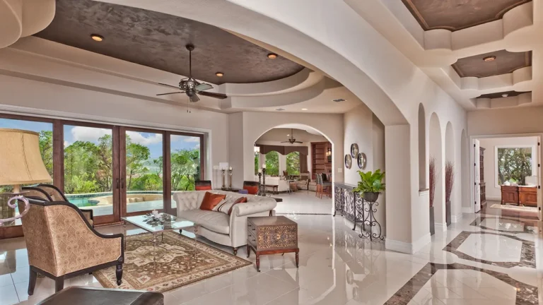 Living room with polished marble floors, a faux-finished tray ceiling and a wall of sliding doors to the pool