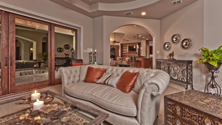 Sitting area with a tufted sofa, wood-framed sliding doors to the covered patio and an arched opening to the kitchen
