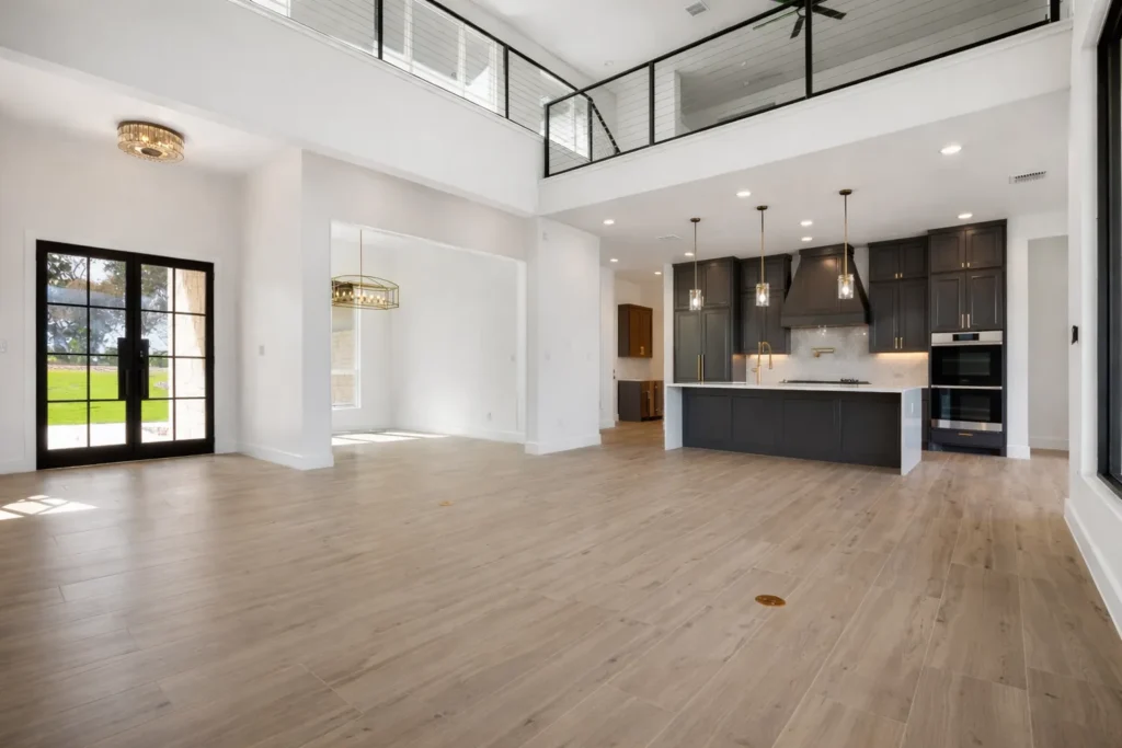 Two-story great room with an overlooking loft catwalk, steel-framed doors and an open kitchen with a dark island