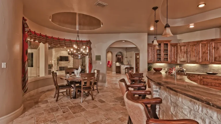 Breakfast room under a round tray ceiling with an iron chandelier, beside a stone-faced kitchen bar and alder cabinetry
