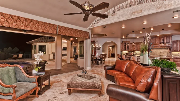 Family room with leather seating, a brick barrel-vault accent and ceiling fan, open to the covered patio, pool and kitchen