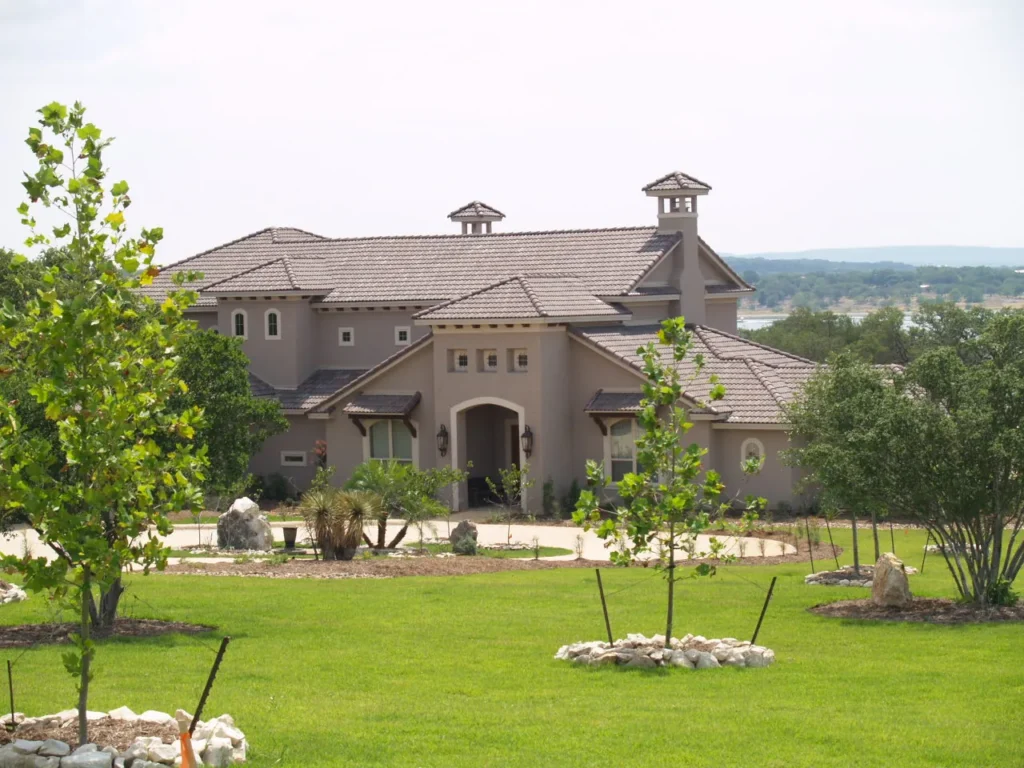 Arched entry and landscaped front lawn of a Genesis custom home in Mystic Shores, Canyon Lake, TX