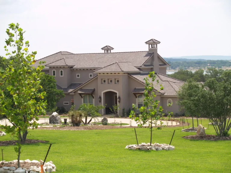 Arched entry and landscaped front lawn of a Genesis custom home in Mystic Shores, Canyon Lake, TX