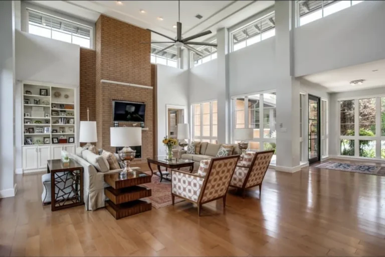 Light-filled living room with a brick fireplace, built-in bookshelves and hardwood floors in a North San Antonio custom home