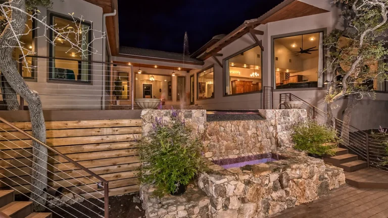 Night view of a natural stone spa, cedar stairs with cable railing and covered outdoor living from the Genesis Custom Homes 2015 Parade of Homes entry