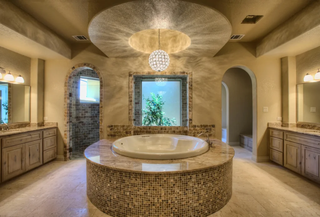 Primary bath with a round mosaic-tile soaking tub beneath a domed ceiling and crystal chandelier in Terra Mont, San Antonio