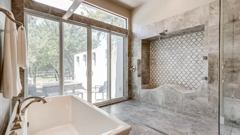 Primary bath with a freestanding tub beside sliding glass doors and a walk-in shower with an arabesque mosaic wall and curved bench