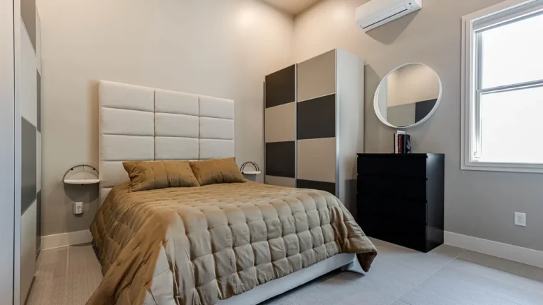 Guest bedroom with a tufted panel headboard, checkerboard wardrobe, round mirror and black dresser