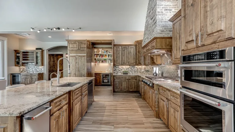 Granite kitchen island with a gooseneck faucet facing knotty alder cabinetry, stainless double wall ovens and a wine bar