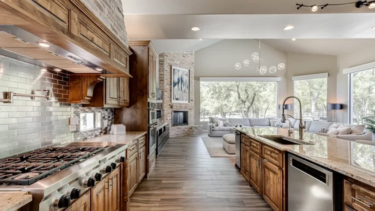 Kitchen range wall with a professional gas cooktop, brick hood, pot filler and granite island open to the living room