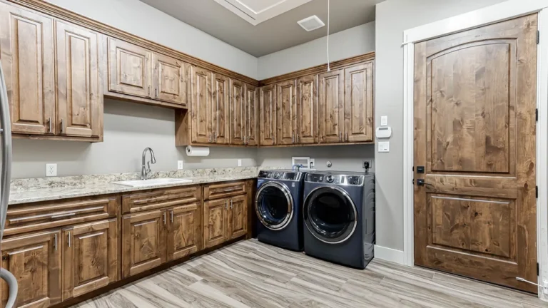 Laundry room with knotty alder cabinetry, granite counters, a utility sink and front-load washer and dryer