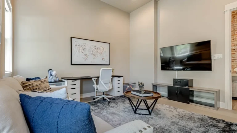 Study with a white desk, mesh office chair, wall-mounted TV and framed world map art above the workspace