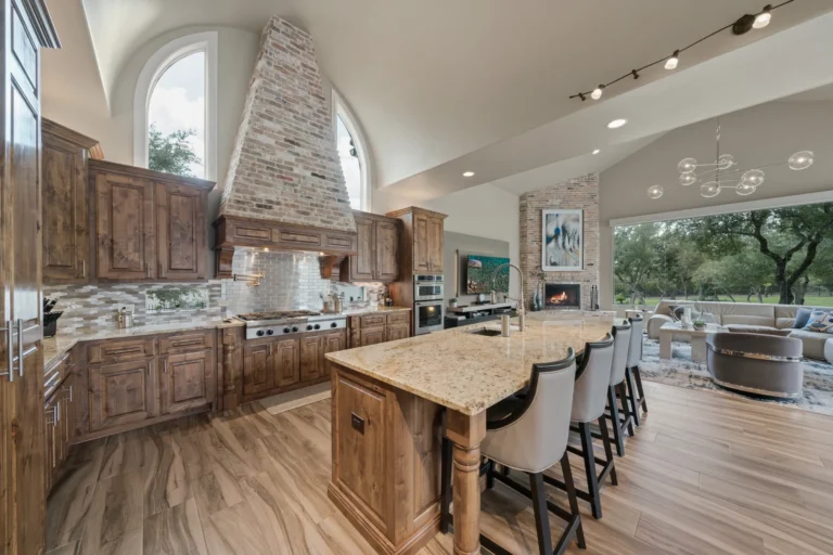 Chef's kitchen in a custom home in The Dominion, San Antonio, with knotty alder cabinets, a brick range hood and a granite island open to the family room